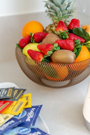 Eine Obstschale mit Erdbeeren, Kiwis, Ananas und Orangen.