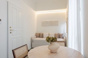Ein Zimmer mit einem runden Tisch, einer weißen Tür, einem Sofa und einer Wandleuchte.