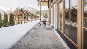 Un bâtiment en bois doté de grandes fenêtres et d’un espace extérieur couvert, aménagé avec une table et des bancs.