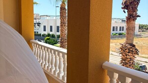 A balcony with a white balustrade, a beige wall, and a view of palm trees and buildings. - Stunning 3-bedroom apartment with a pool – Ideally located in La Zenia! (Orihuela)