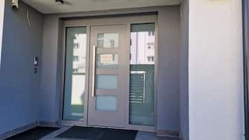 A building entrance with a double door, a small overhang, and a security camera.
