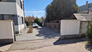 A narrow street with a white car parked on the side, flanked by buildings with a mix of modern and traditional architecture. - Premium 2-bedroom apartment with 2 bathrooms, balcony and private entrance. (Budapest)