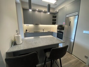 Una cocina moderna con encimeras de granito, electrodomésticos de acero inoxidable y una isla central con taburetes de bar.