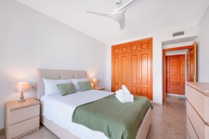 A bedroom with a bed, nightstands, a ceiling fan, wooden wardrobe, and a door leading to another room. - LXR Maison du Soleil 2-Bedroom Near the Sea (Benalmádena)