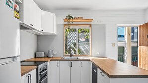Una cocina moderna con armarios blancos, encimera de madera, horno empotrado y ventana con vistas al verdor.