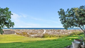 Un paisaje costero con una zona cubierta de hierba, un camino y vista al mar.