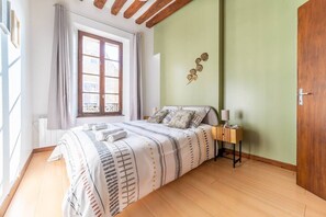 Et soveværelse med en seng, et natbord, en lampe, et vindue og en dør.
