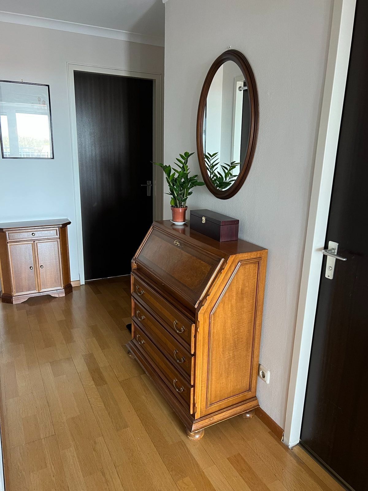A room with a wooden dresser, a mirror, and a potted plant.