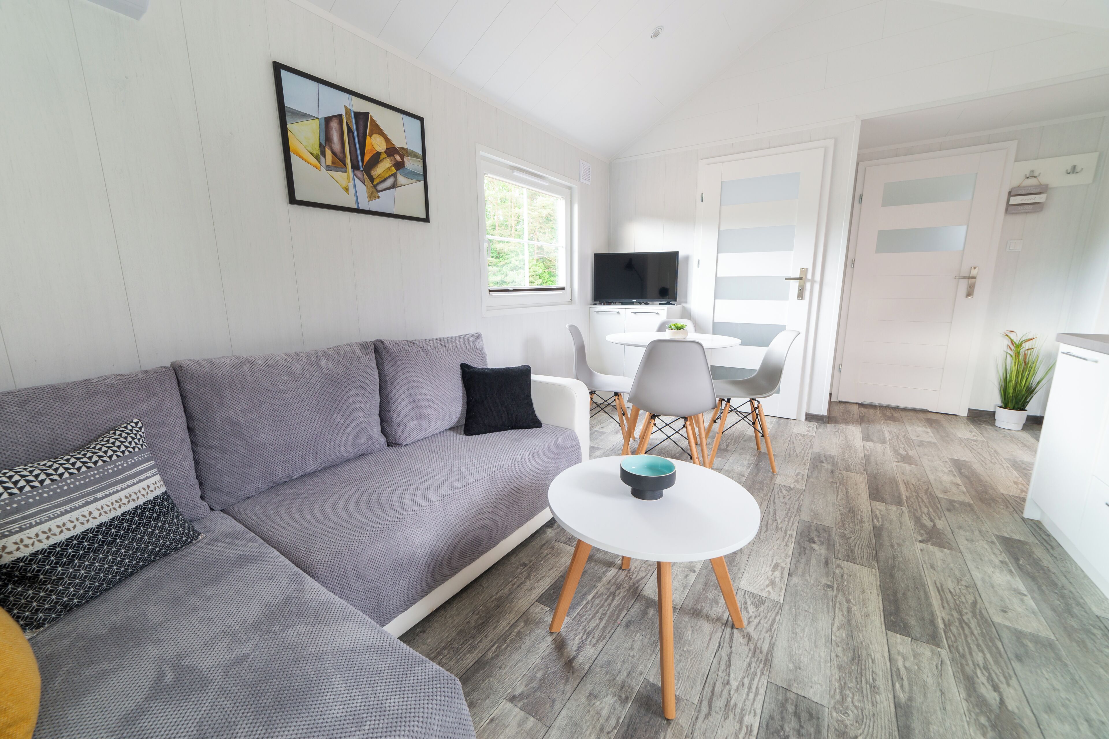 En moderne stue med en grå sofa, et hvidt sofabord og et fjernsyn.