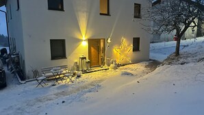 A snow-covered front yard with a bench, a chair, and a star-shaped light decoration. - Villa Barka – 5-Star Vacation Rental in the Bavarian Forest Near the National Park (Eppenschlag)