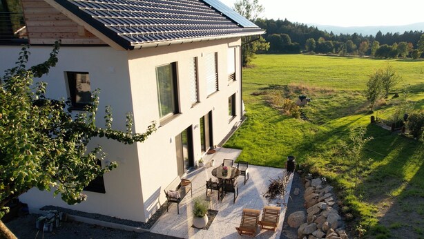 A modern house with a patio, outdoor seating, and a view of a green field. - Villa Barka – 5-Star Vacation Rental in the Bavarian Forest Near the National Park (Eppenschlag)
