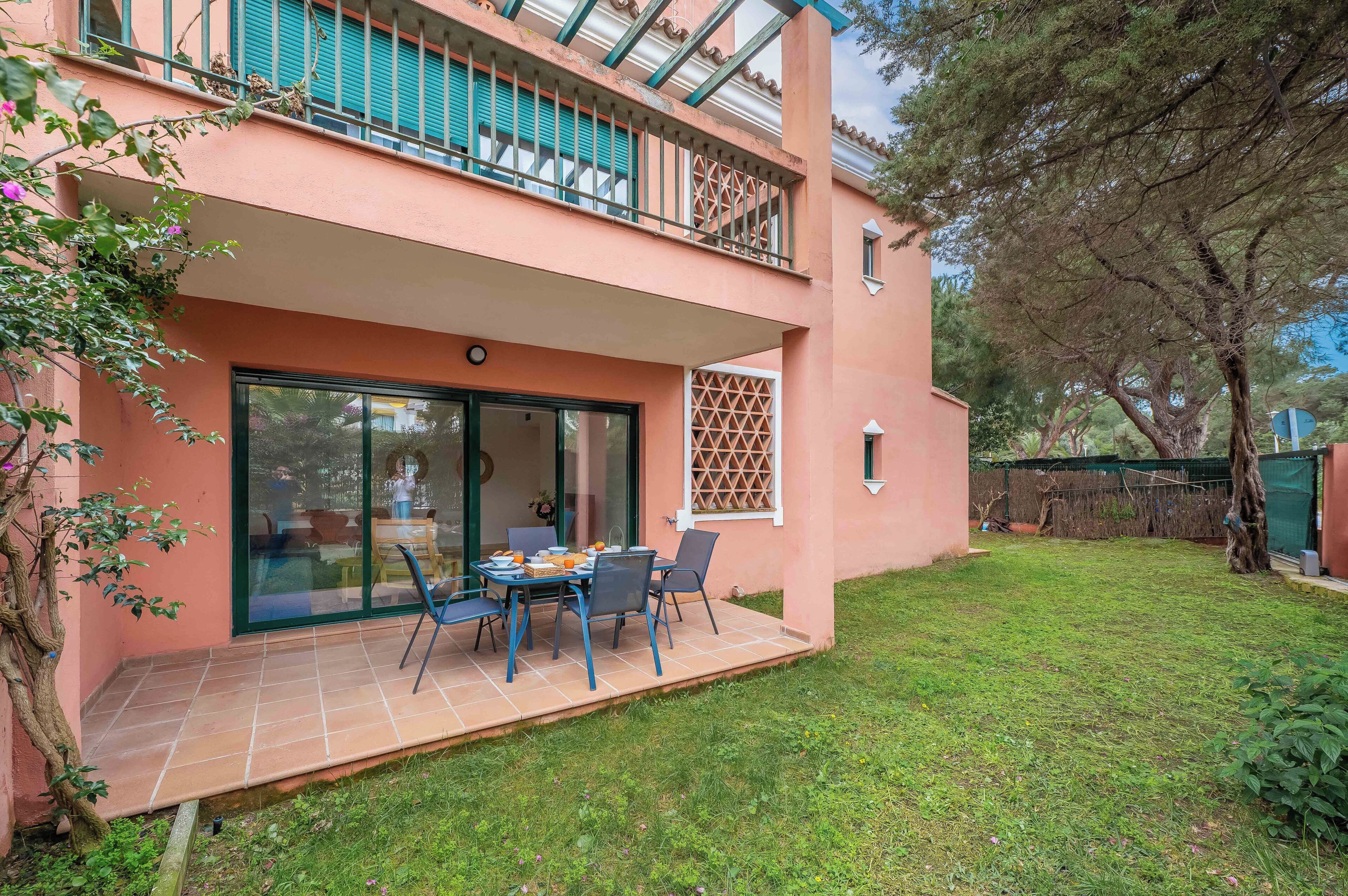 A two-story building with a covered patio, a dining table with chairs, and a glass door entrance.