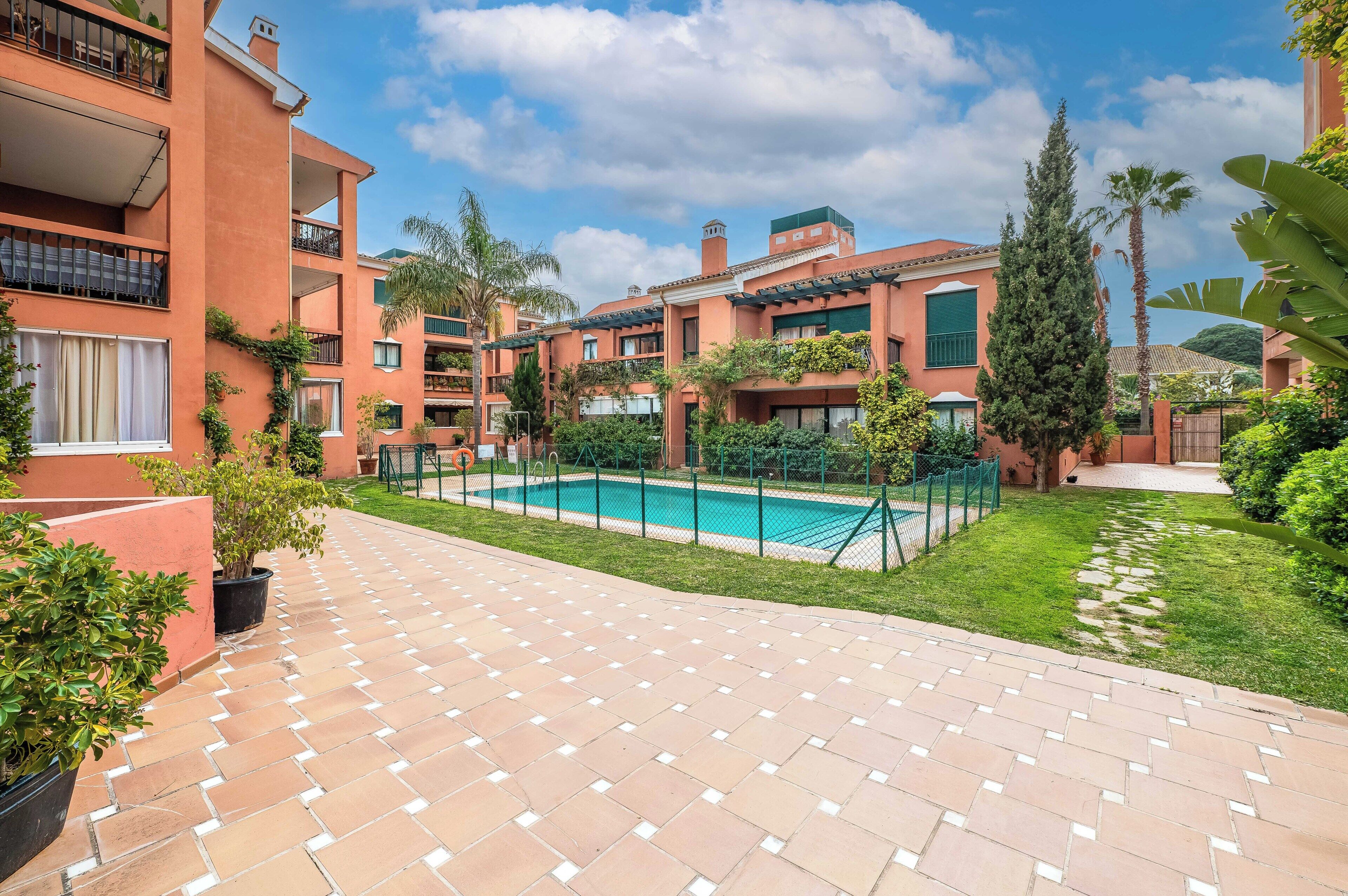 A courtyard with a swimming pool, potted plants, and a tiled walkway.