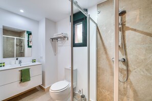 A bathroom with a glass-enclosed shower, a toilet, a sink with a mirror, and a towel rack. - LXR Marbesa 1-Bedroom Near the Sea (Marbella)