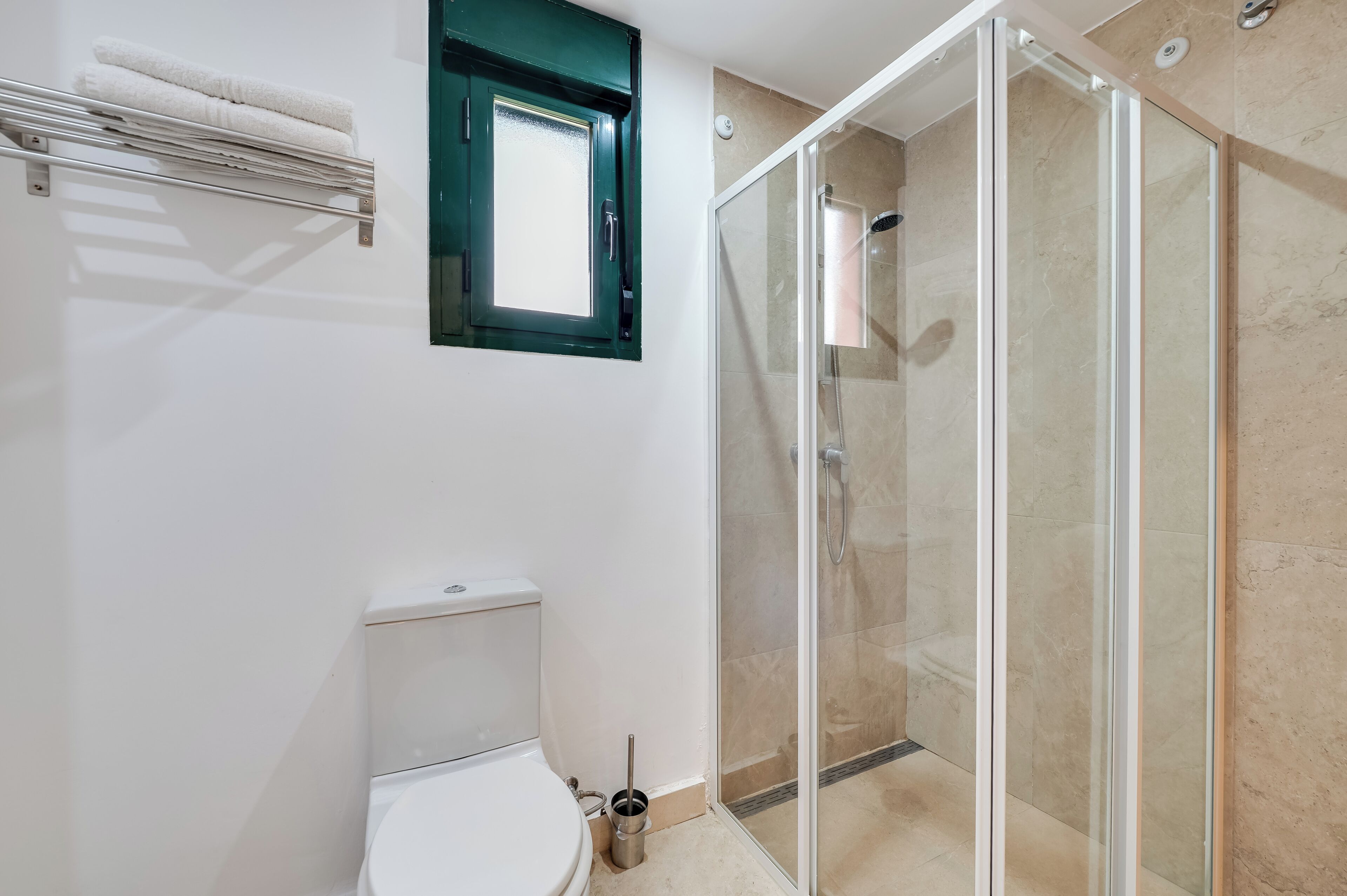 Une salle de bain comprenant des toilettes, une douche fermée par une paroi de verre et un porte-serviettes.