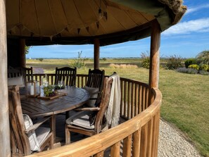 A wooden deck with a round table and chairs, overlooking a grassy landscape. - Fantastic Large Chichester Harbour View House. 2 minutes to beach. (Hayling Island)
