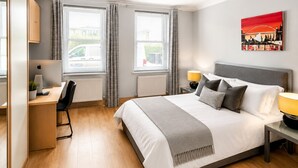 Une chambre à coucher avec un lit, un bureau, une chaise et des fenêtres.