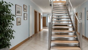 Un escalier moderne avec une rampe en métal et des marches en bois, menant à l’étage supérieur.