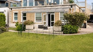 Une maison à deux étages avec un balcon, une cour clôturée et un ciel dégagé.