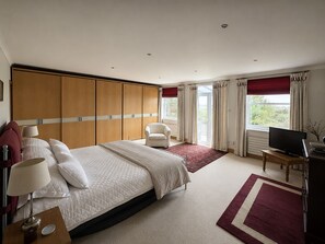 A hotel room with a large bed, a seating area with a chair, a television, and a desk. - Fantastic Large Chichester Harbour View House. 2 minutes to beach. (Hayling Island)