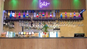 A bar area with a neon sign, shelves with colorful bottles, and a variety of glasses. - Standard Twin Room (Norwich)