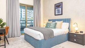 Un dormitorio con cama, mesitas de noche, un escritorio y una silla.