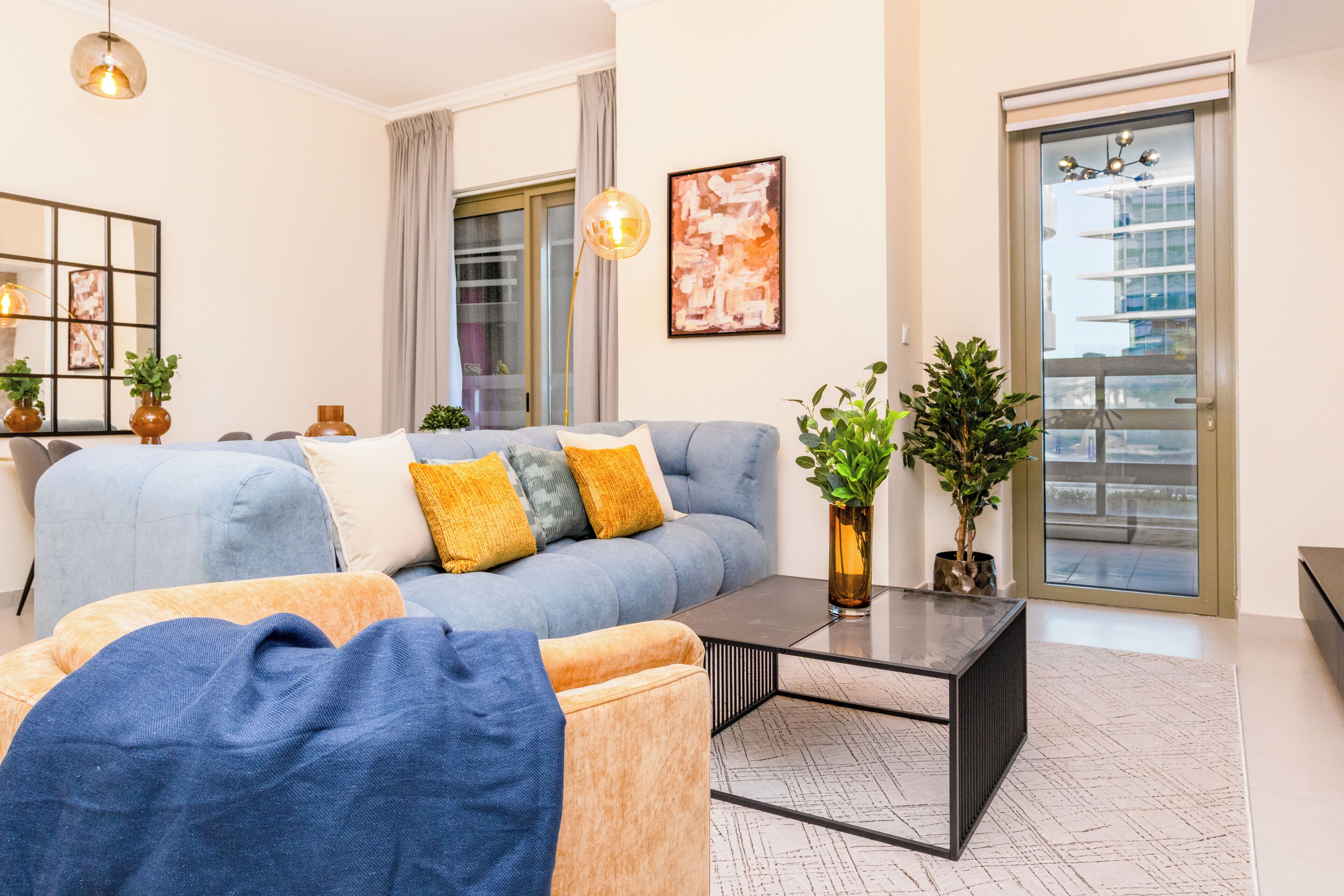 A modern living room with a sofa, coffee table, and potted plants.