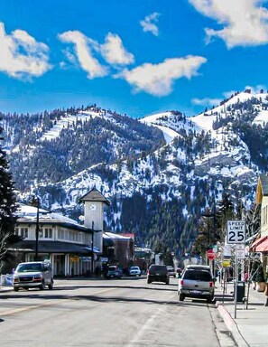 Une ville avec un beffroi, un panneau indiquant la limite de vitesse et, en arrière-plan, des montagnes enneigées.