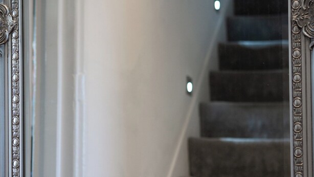 Eine Treppe mit Teppichstufen und Wandleuchten.