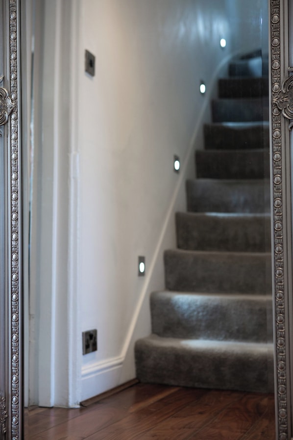 Una escalera con peldaños alfombrados y luces fijadas a la pared.