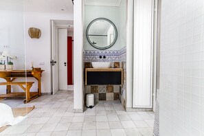 A bathroom with a round mirror, a white sink, and patterned tiles. - Tavira Bliss Garden Apartment (Tavira)