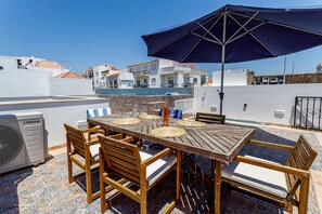 Een dakterras met een eettafel, buitenterras en een grote parasol voor de schaduw.