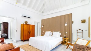 Ein Schlafzimmer mit einem Bett, einem Holzschrank, einem Nachttisch, einer Lampe und einer dekorativen Wandverkleidung.