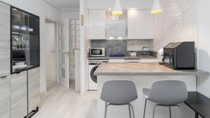 A modern kitchen with a central island, two bar stools, a microwave, a coffee machine, and a dishwasher. - Modern apartment in downtown Somo. 3 minutes from the beach. (Somo)