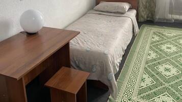 A bedroom with a bed, a wooden desk, a television, and a wardrobe.
