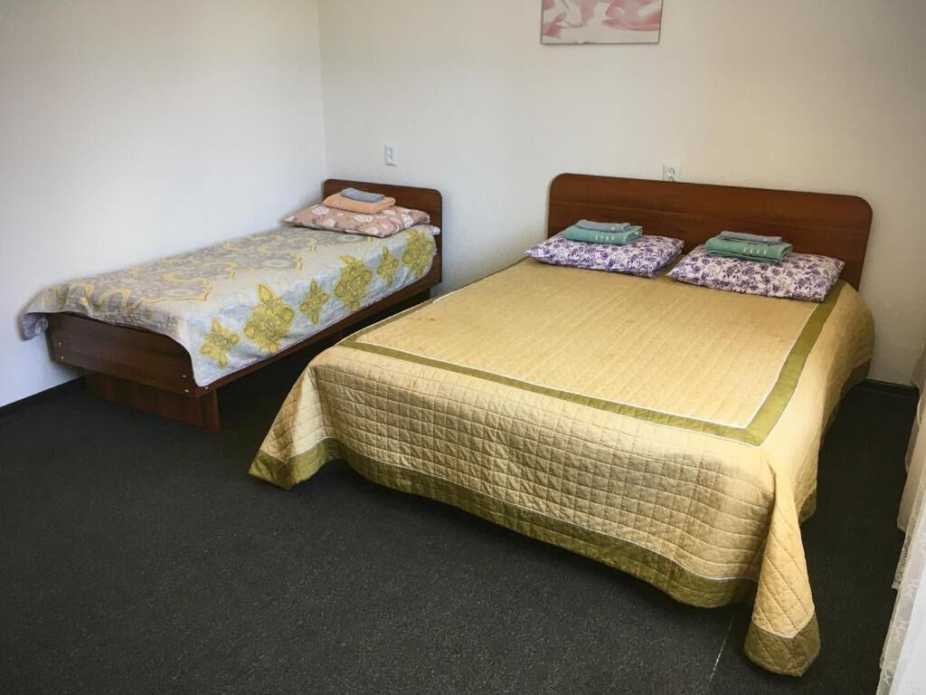 Dos camas en una habitación con piso alfombrado y pared lisa.