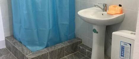 A bathroom with a blue shower curtain, a sink, a toilet, and a mirror.