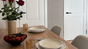 A dining table set with plates, a bowl of fruit, and a vase with flowers.
