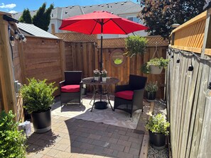 A patio with wicker chairs, a red umbrella, and potted plants. - The Whitby Hideaway - a modern space on a quiet stree wih a private patio area. (Whitby)