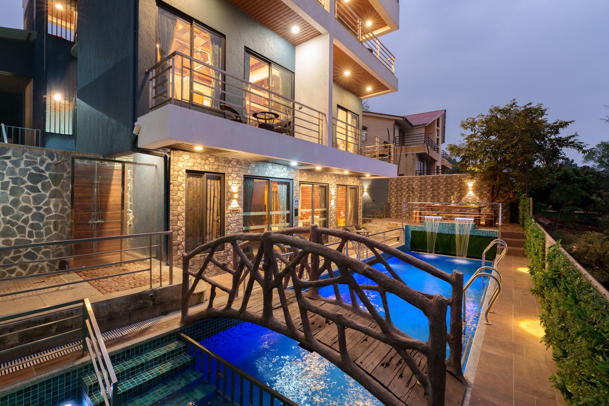 A multi-story hotel with a swimming pool, stone facade, and balconies.