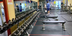 Ein Fitnessstudio mit Reihen von Kurzhanteln, Bänken und Kraftgeräten.
