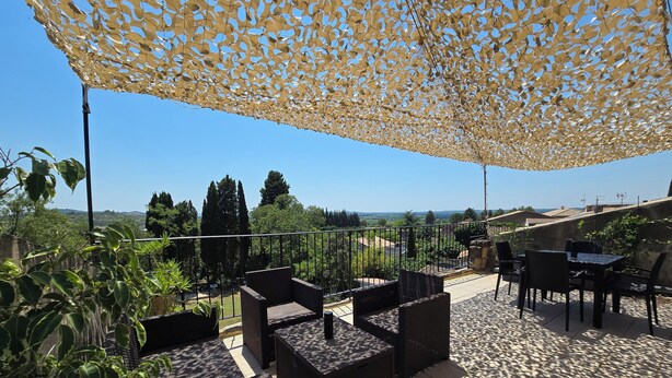 En udendørs terrasse med siddepladser, udsigt over landskabet og en pergola.