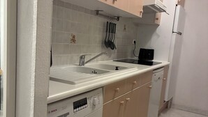 Une cuisine de taille réduite, équipée d’un lave-linge, d’un évier et de placards.