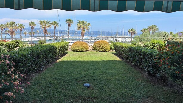 Un jardin avec un sentier menant à une marina où sont amarrés des bateaux.