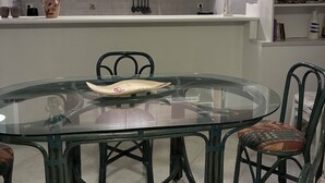 Une cuisine moderne avec une table à manger en verre, des chaises et un réfrigérateur blanc.