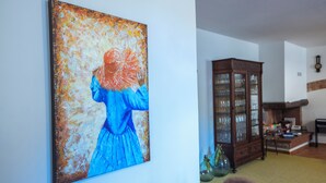 A room with a large abstract painting on the wall, a wooden cabinet with glass doors, and a clock on the wall. - Mulino La Sosta (Camaiore)