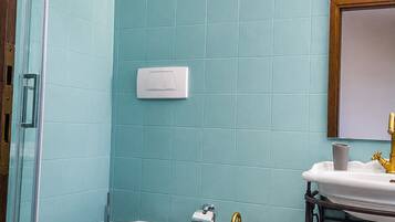 A bathroom with two toilets, a sink, a mirror, and a trash bin.