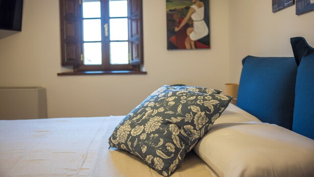 A bedroom with a bed, a window, and a painting on the wall. - Mulino La Sosta (Camaiore)