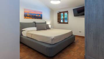 Una camera da letto con un letto, una finestra vista, un quadro appeso al muro e una televisione a parete.