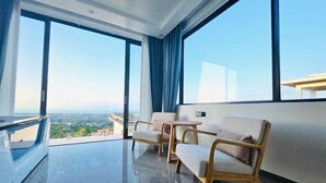 Een moderne kamer met grote ramen, een balkon en uitzicht op de stad.
